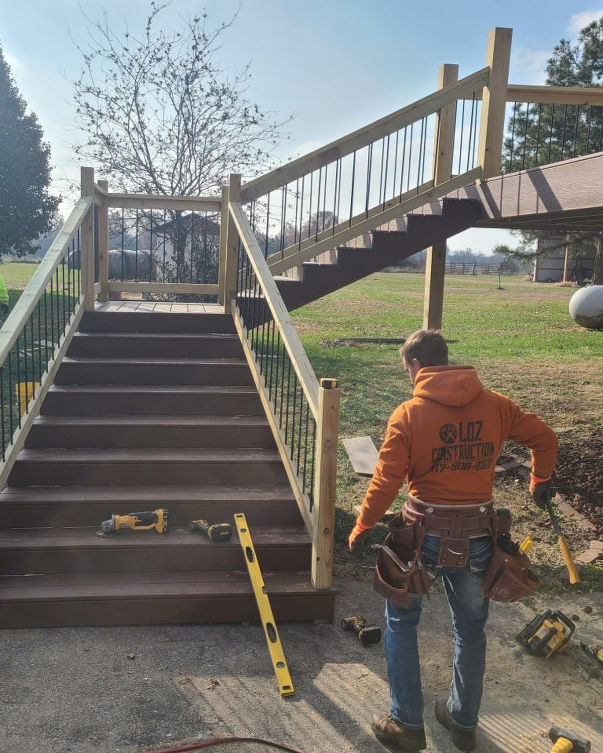L.O.Z. Construction crew member in a company hoodie finishing new composite deck stairs