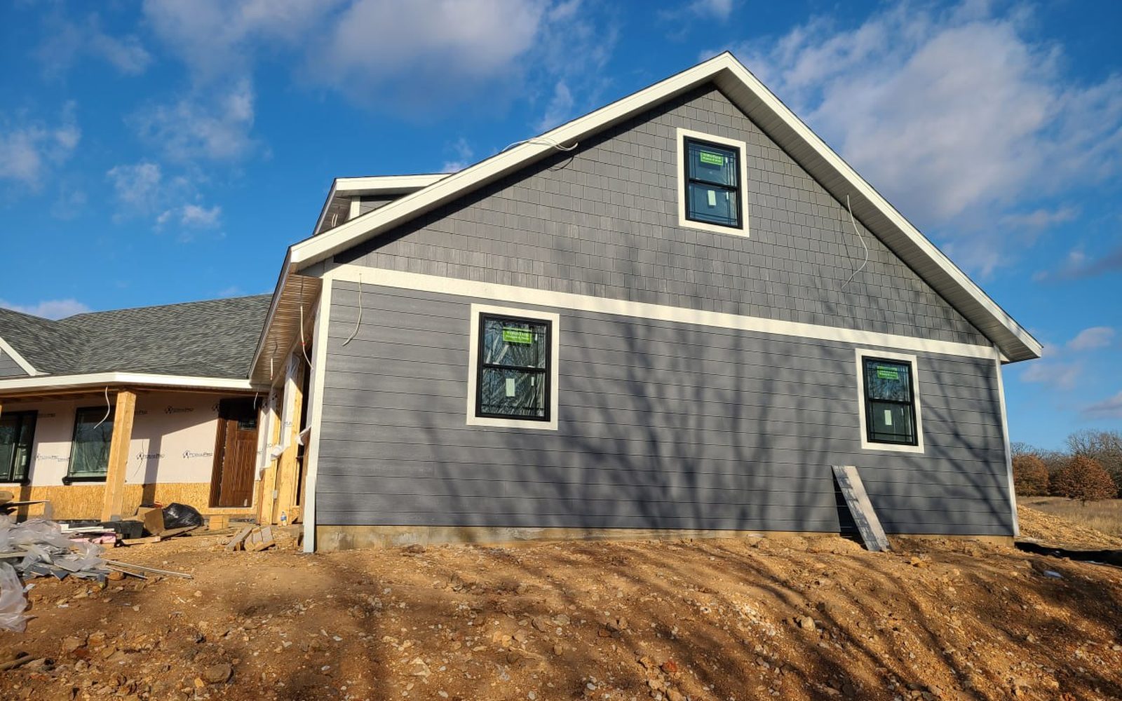 Gable end of a gray-sided custom home with shake accents built by L.O.Z. Construction