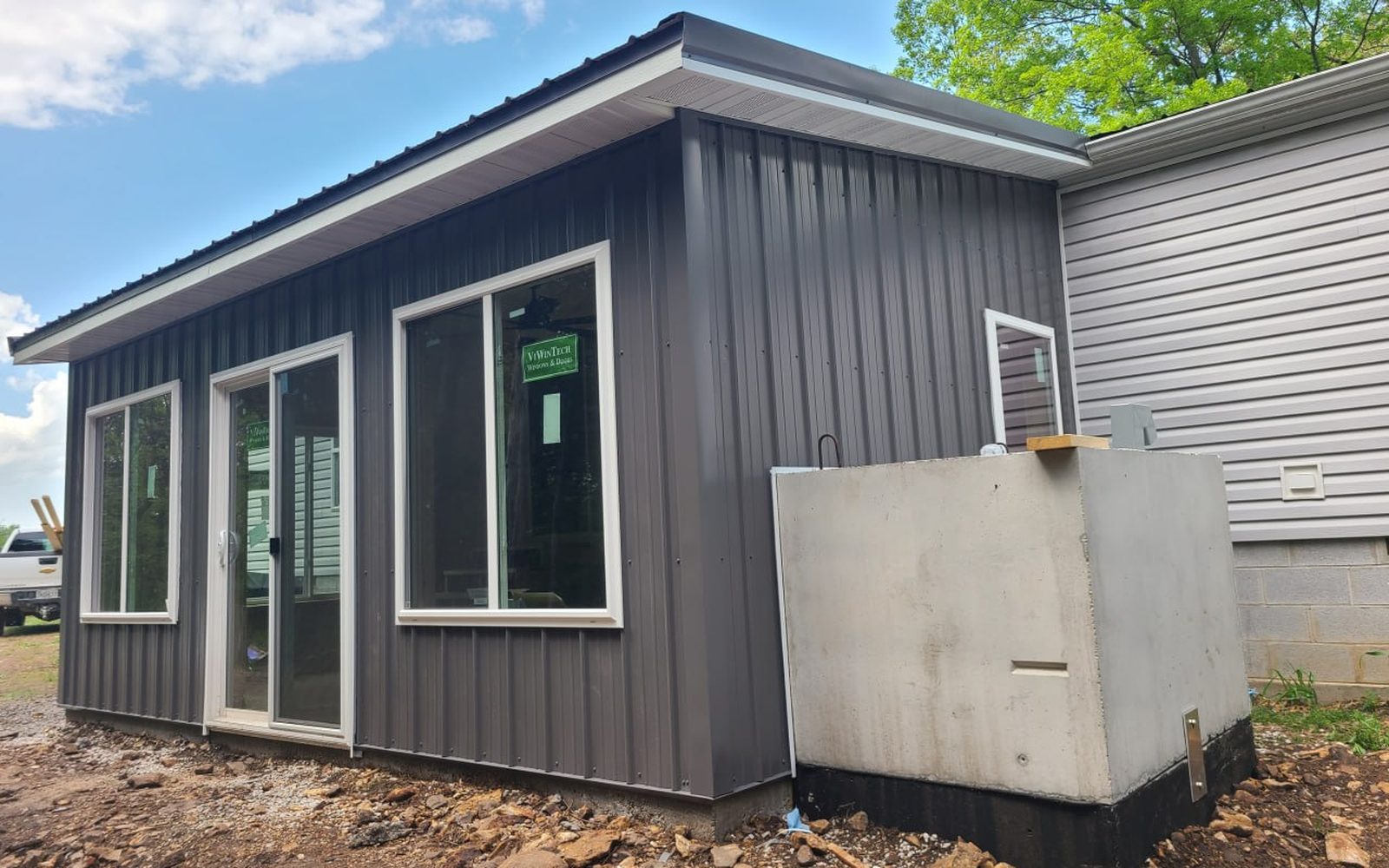 Dark metal-sided sunroom addition with a concrete storm shelter built by L.O.Z. Construction