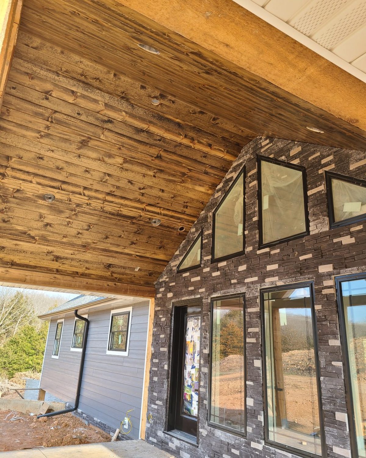 Stained pine porch ceiling and stone veneer on a custom home built by L.O.Z. Construction