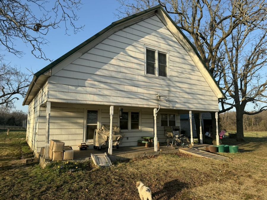 Older white farmhouse with a worn porch and turned columns before renovation
