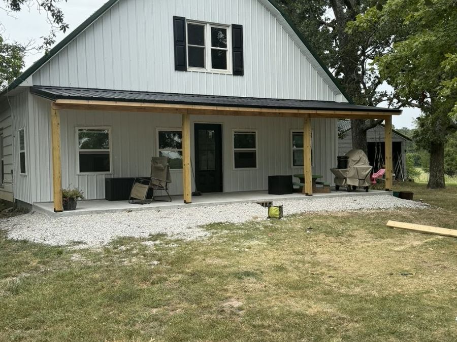 White metal-sided home with a new covered porch on timber posts built by L.O.Z. Construction