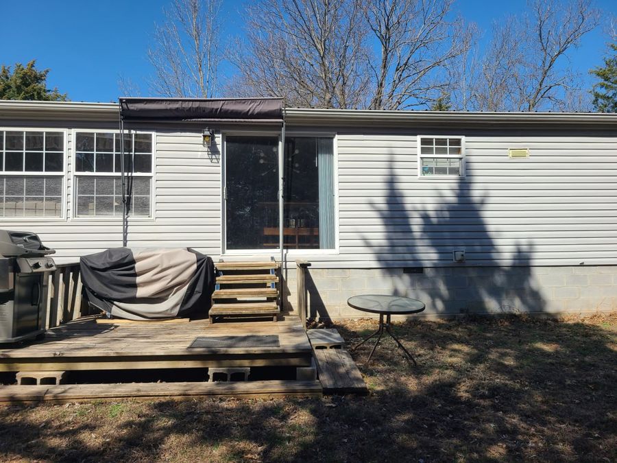 Back of a manufactured home with a small wood deck before the sunroom was added