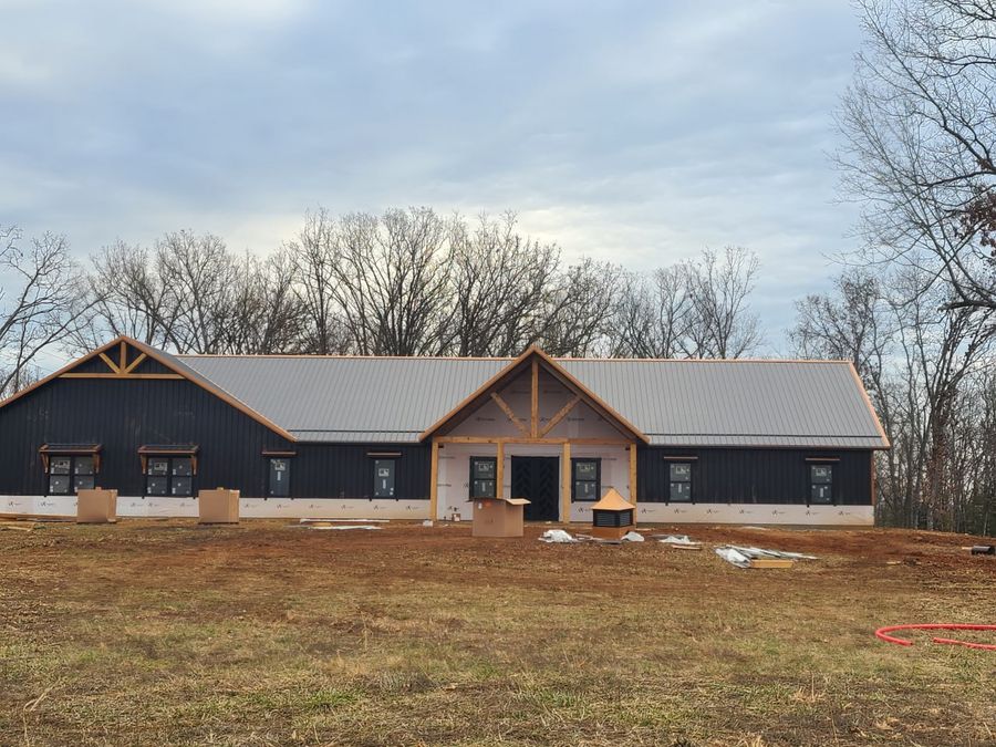 Black metal-sided custom home with timber gable trusses and a gray metal roof