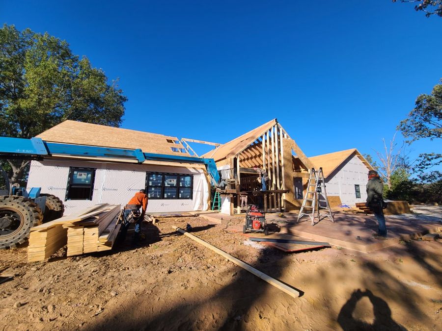 L.O.Z. Construction crew framing a custom home with a boom lift under a clear blue sky