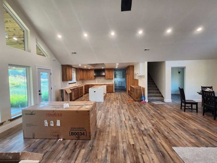 Great room with a vaulted ceiling looking toward an oak kitchen and open staircase