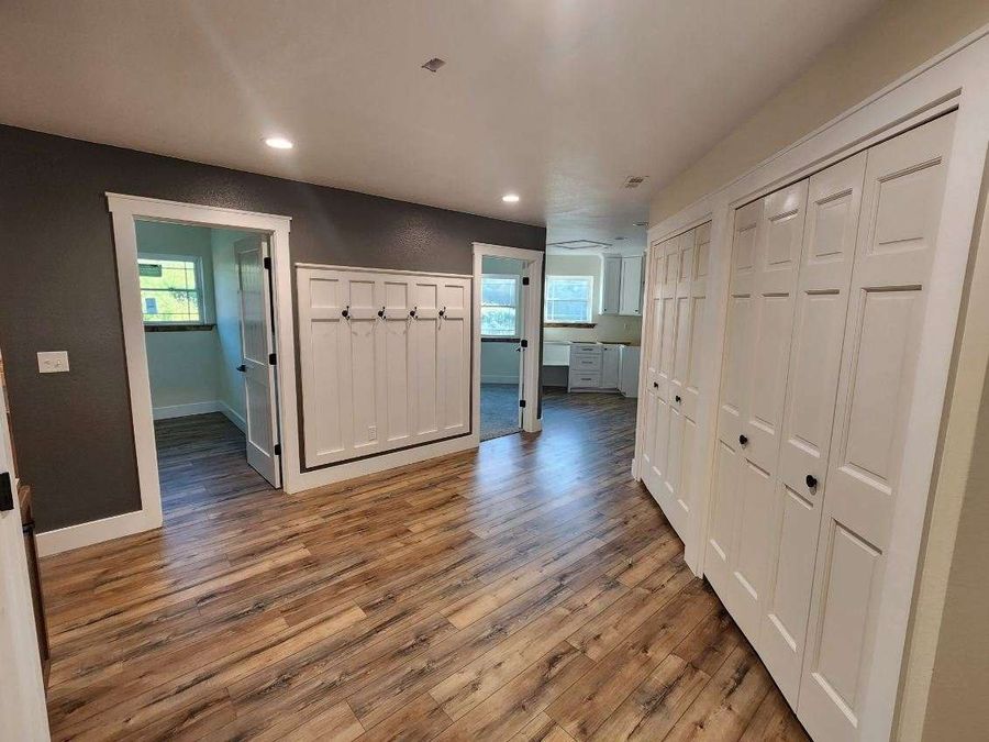 Mudroom with white board-and-batten coat hooks, closet doors and wide-plank flooring
