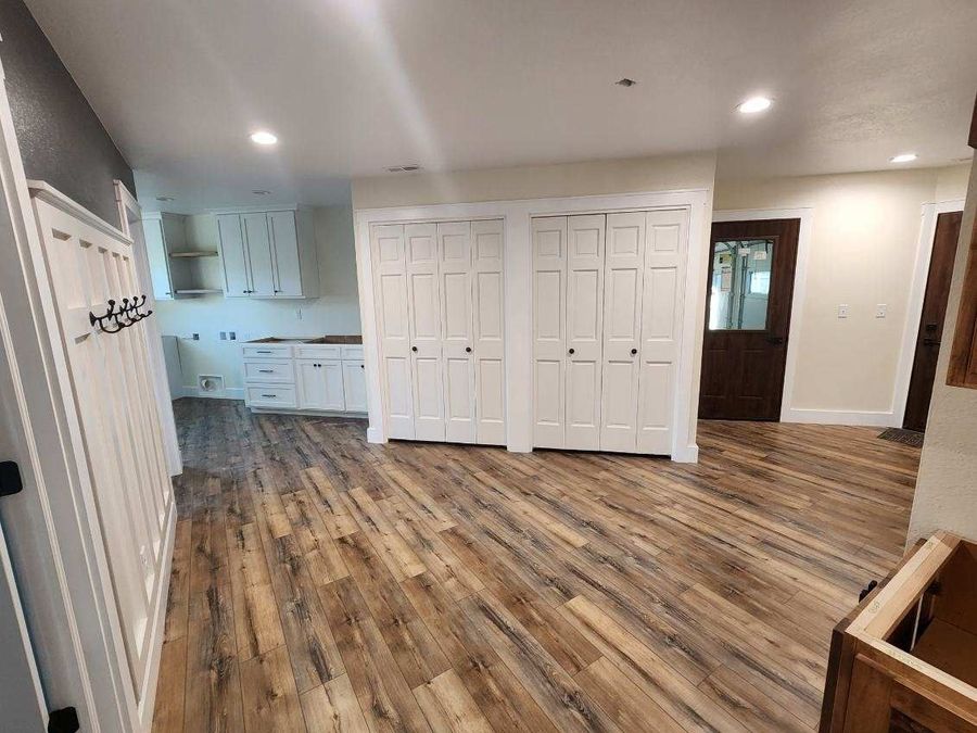 Hallway with wide-plank flooring, double closets and white cabinets in a laundry nook