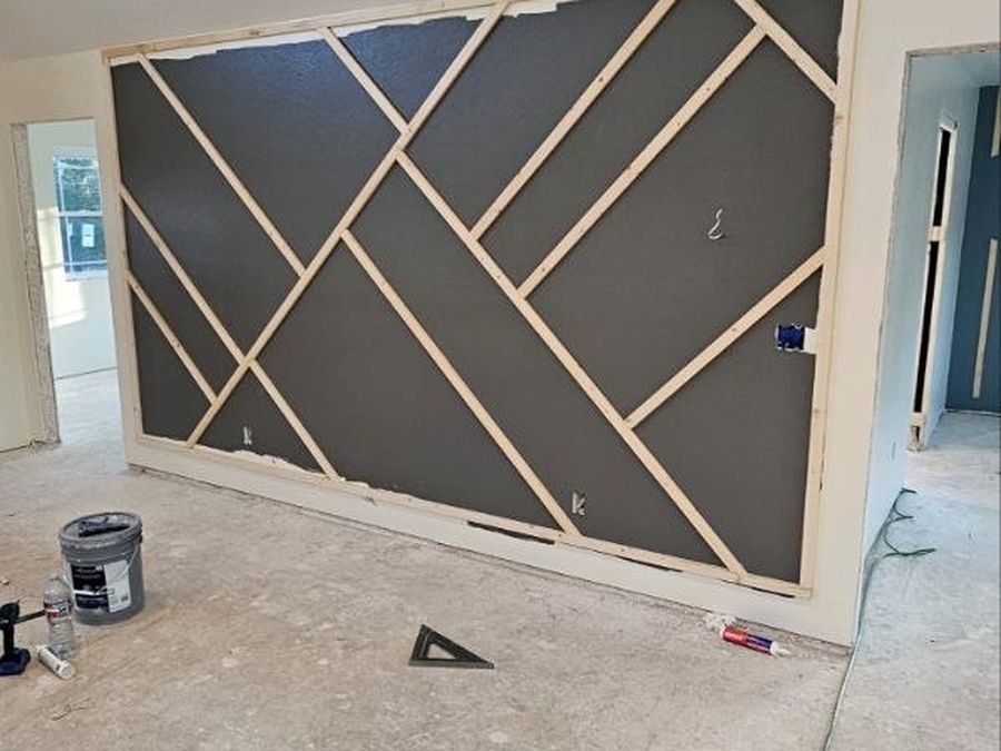 Geometric trim accent wall laid out with raw boards before paint