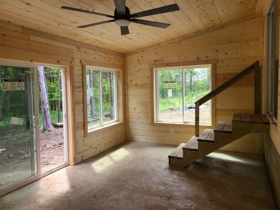 Finished pine sunroom with a sliding glass door, windows and steps up to the house