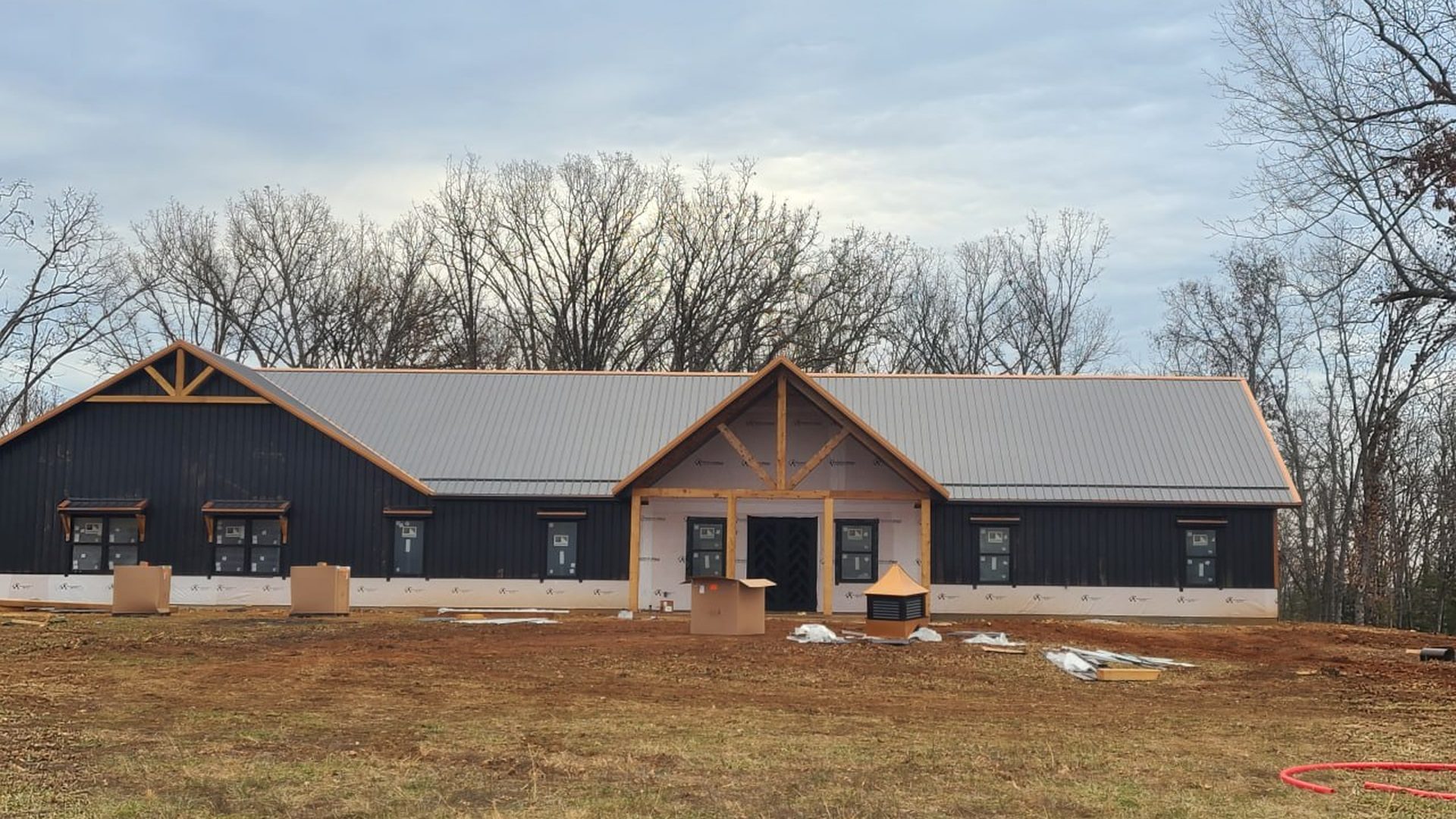 Black metal-sided custom home with timber gable trusses built by L.O.Z. Construction
