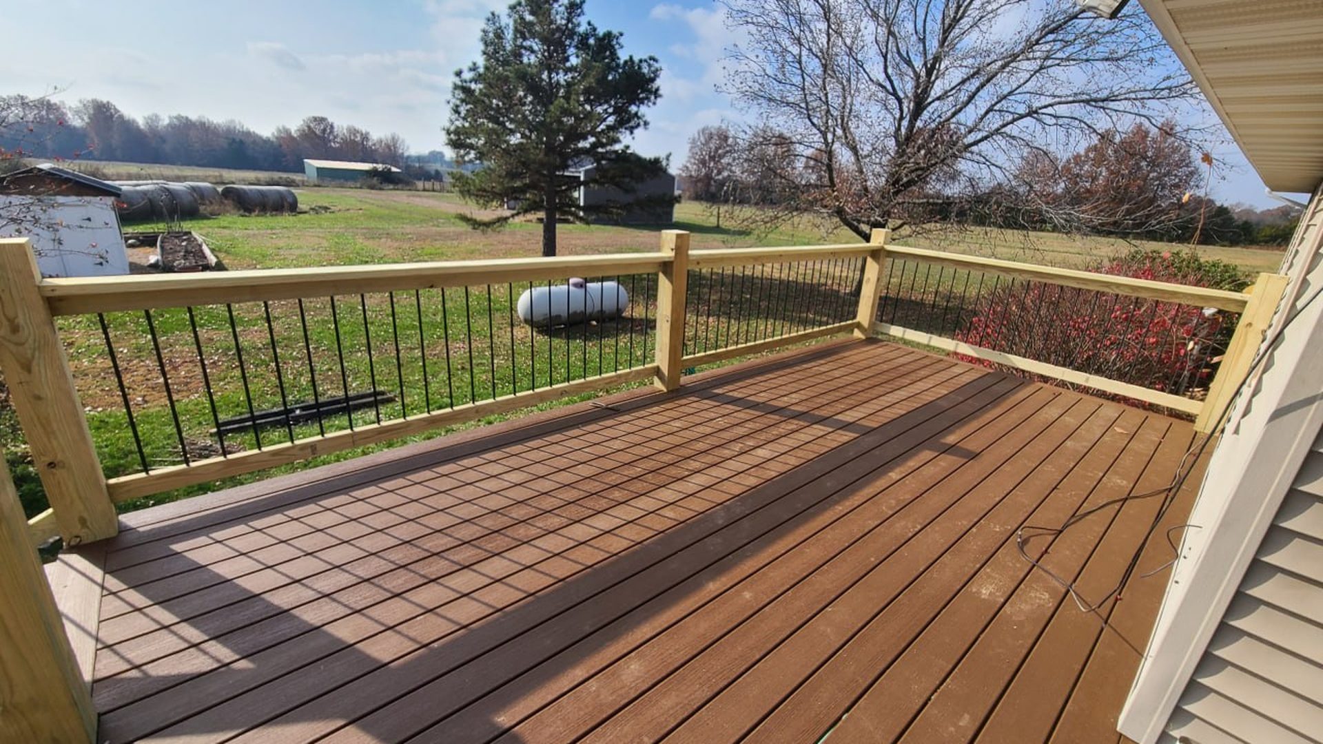 Finished composite deck with black baluster railing overlooking a Missouri field
