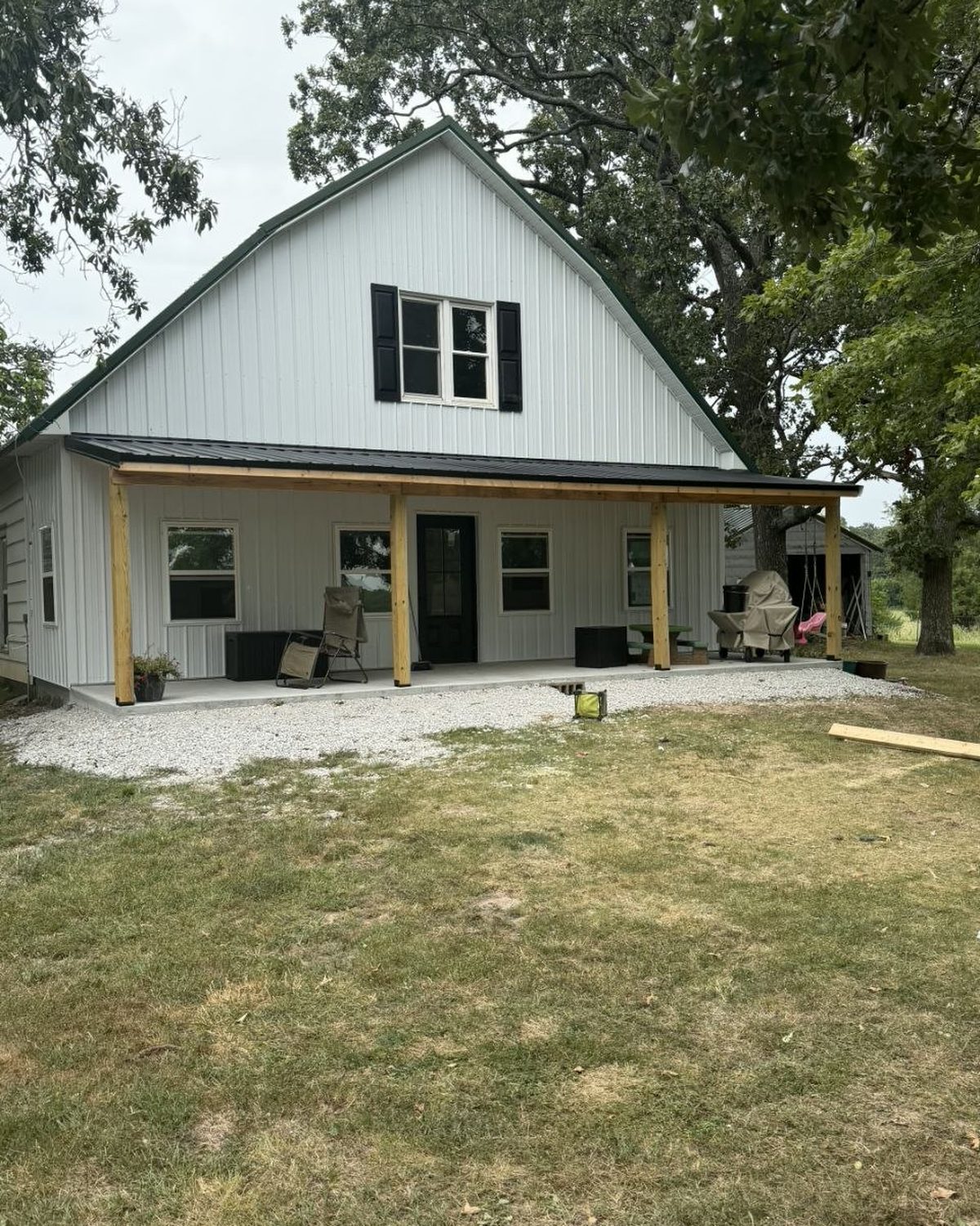 White metal-sided home with a new covered porch on timber posts built by L.O.Z. Construction