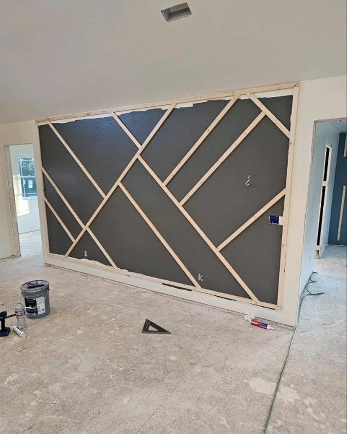 Geometric trim accent wall laid out with raw boards before paint in a new custom home