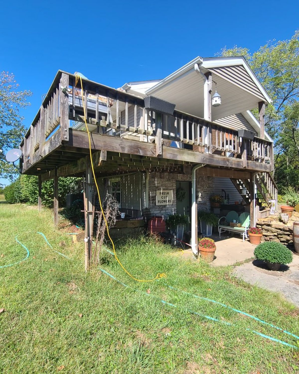 Weathered wood deck on tall posts before L.O.Z. Construction tore it out and rebuilt it